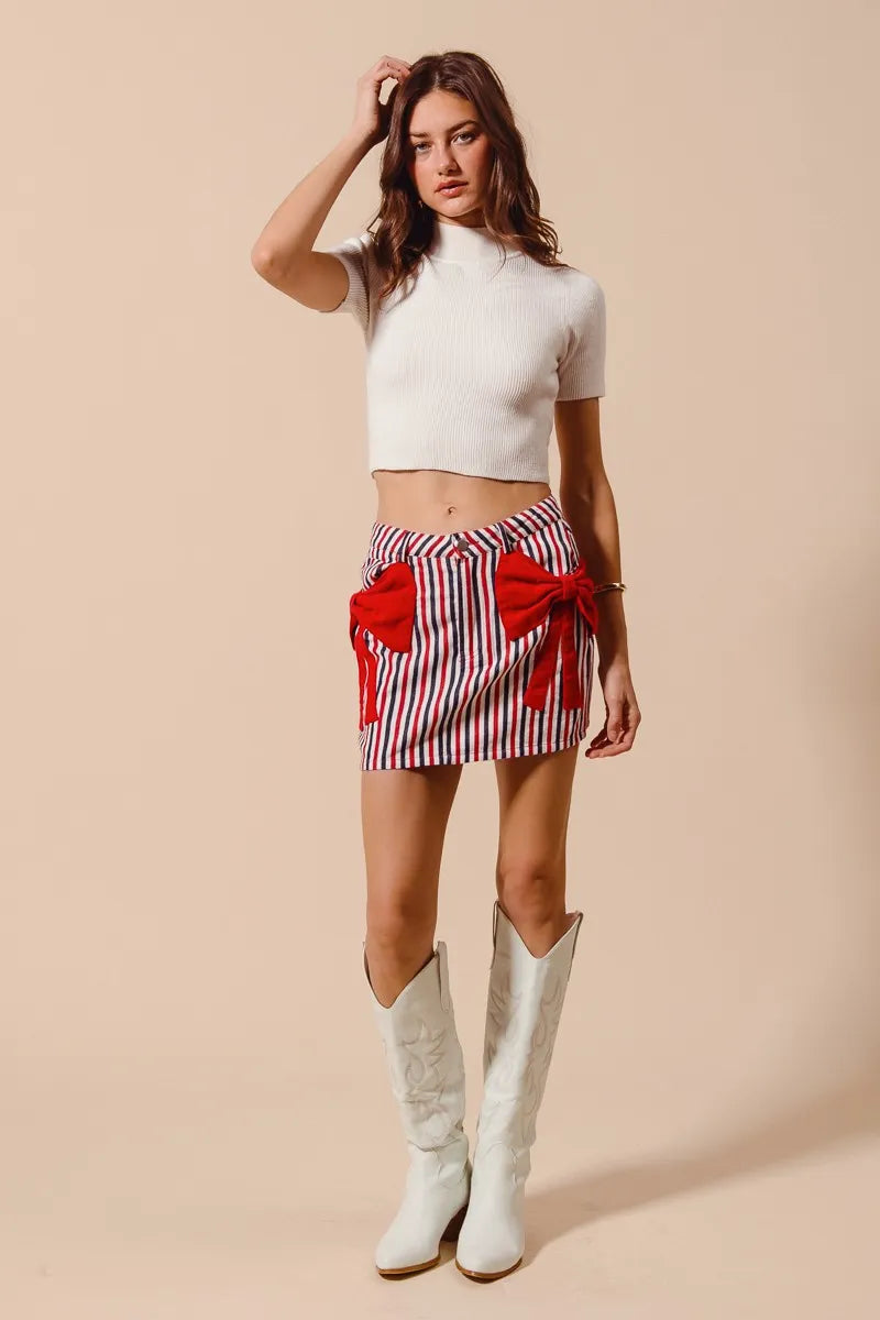 Striped denim mini skirt with red bow accent and front pocket ribbon detail