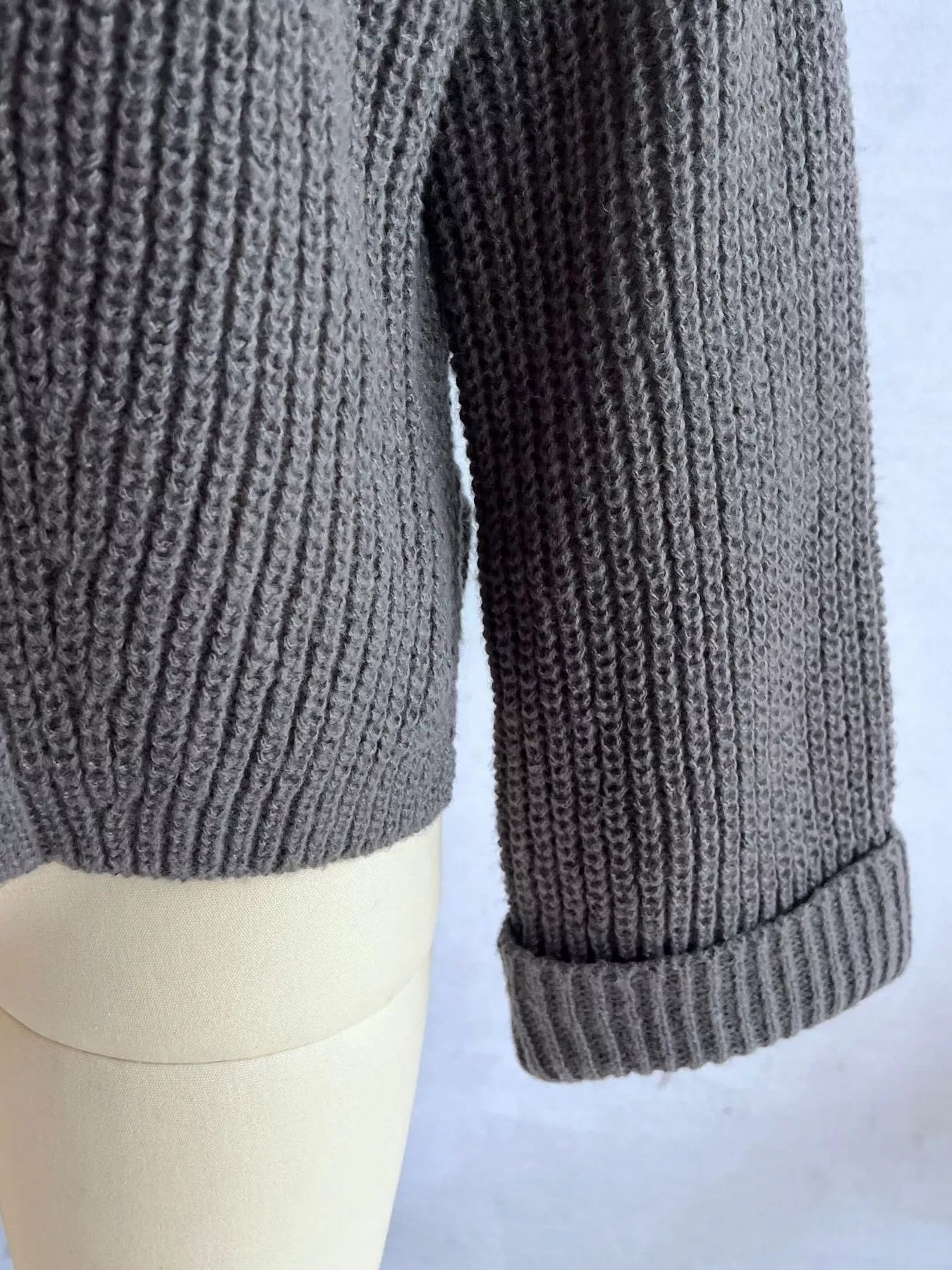 Asymmetrical button detail sweater in gray knit with ribbed cuff and curved hem