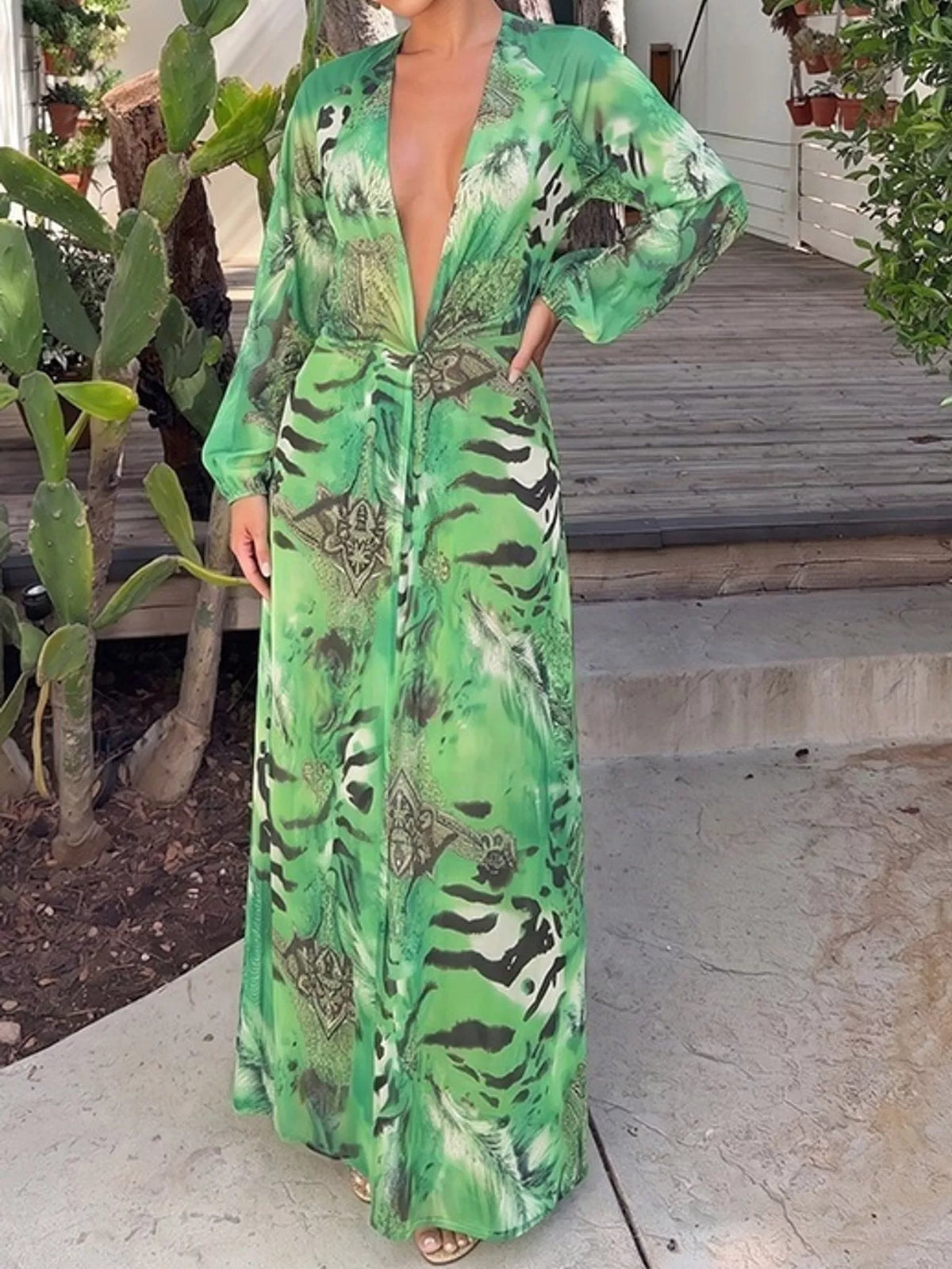 Green printed maxi dress with deep V-neck, long sleeves, and flowing skirt hem
