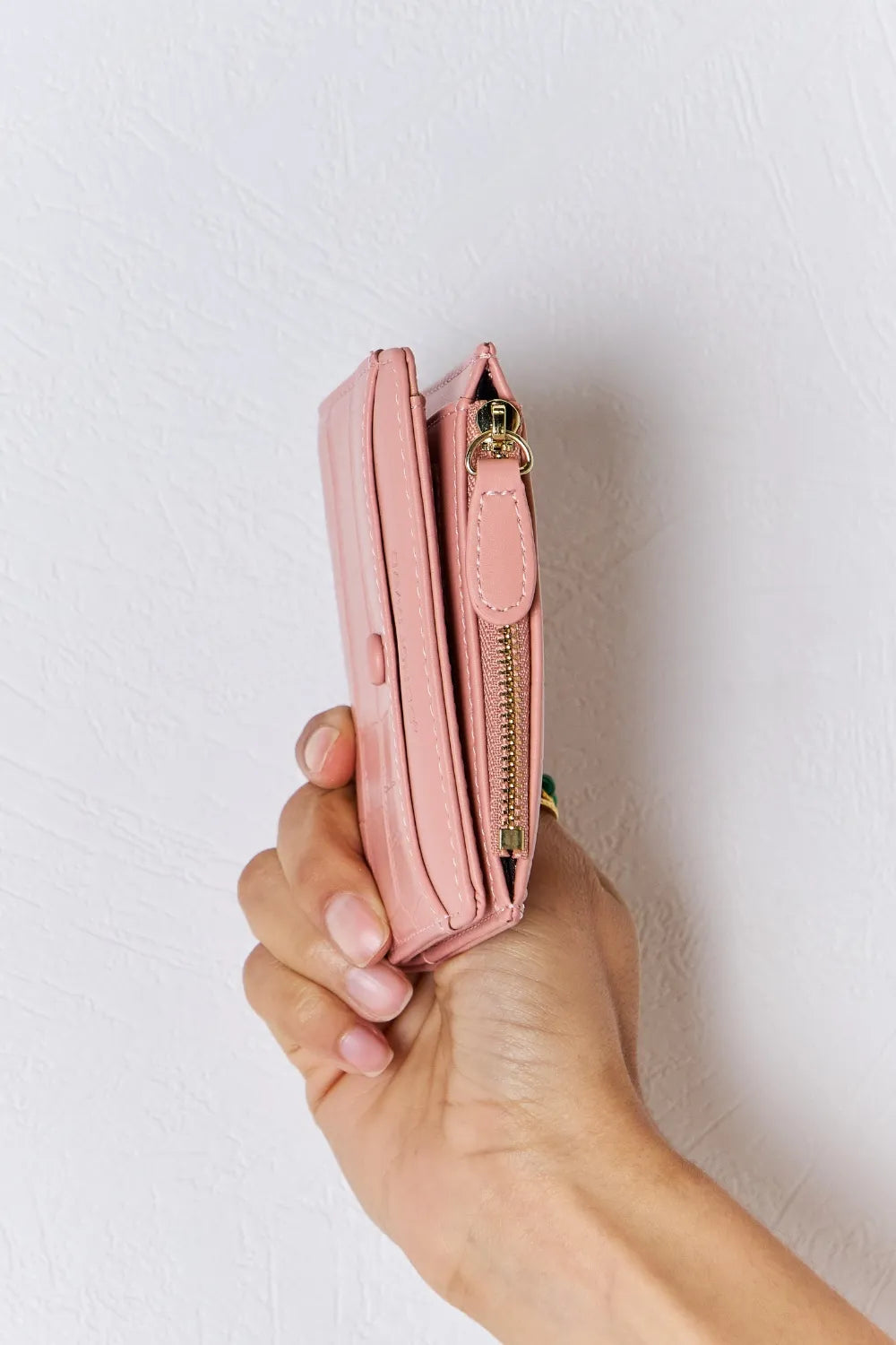 Pink textured vegan leather mini wallet side view with gold zipper hardware.