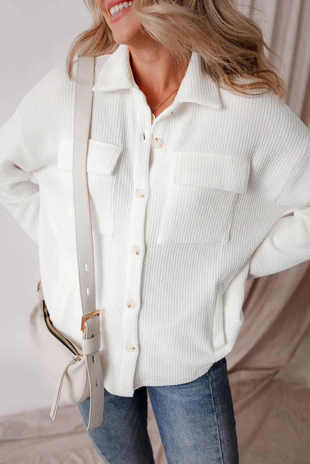White long-sleeve shacket with button front and two chest pockets, side seam visible.