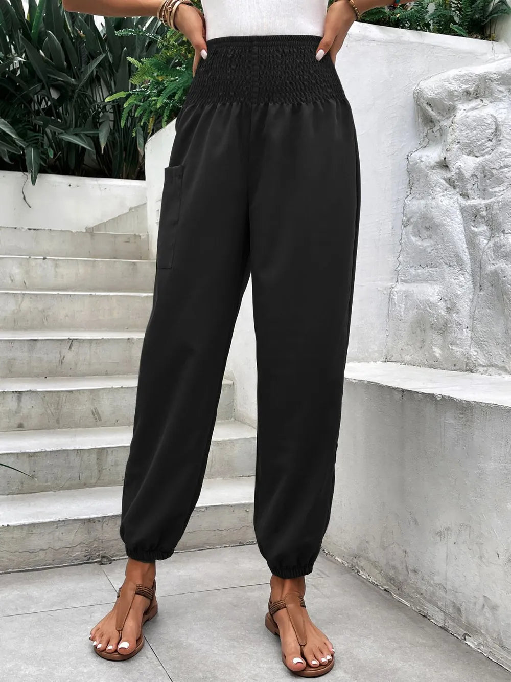 Black smocked high-rise joggers with side pockets and relaxed tapered legs