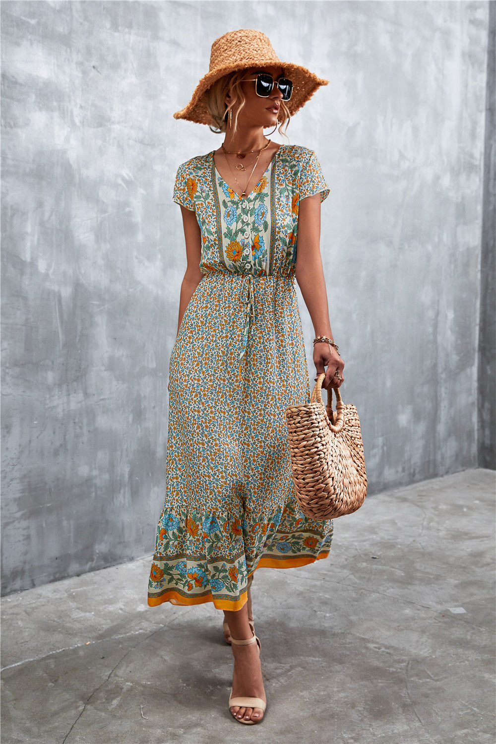 V-neck printed maxi dress with short sleeves, beige base with teal floral trim at the hem.