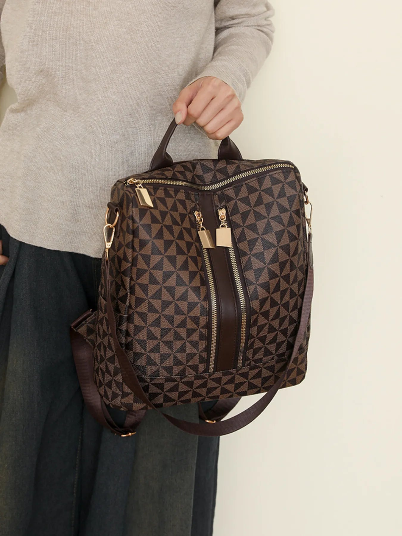 Geometric pattern backpack bag in brown with gold-tone zippers and side strap, front view
