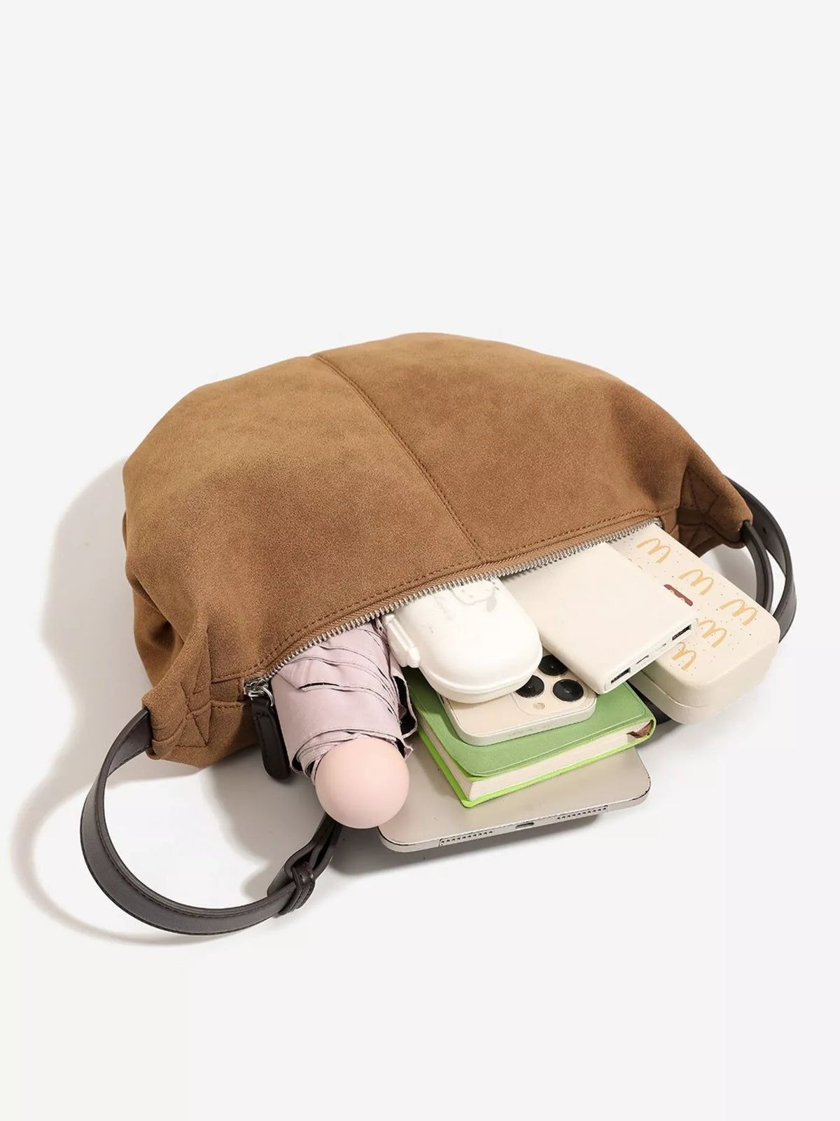 Brown suede crescent shoulder bag with zipper top and visible interior items