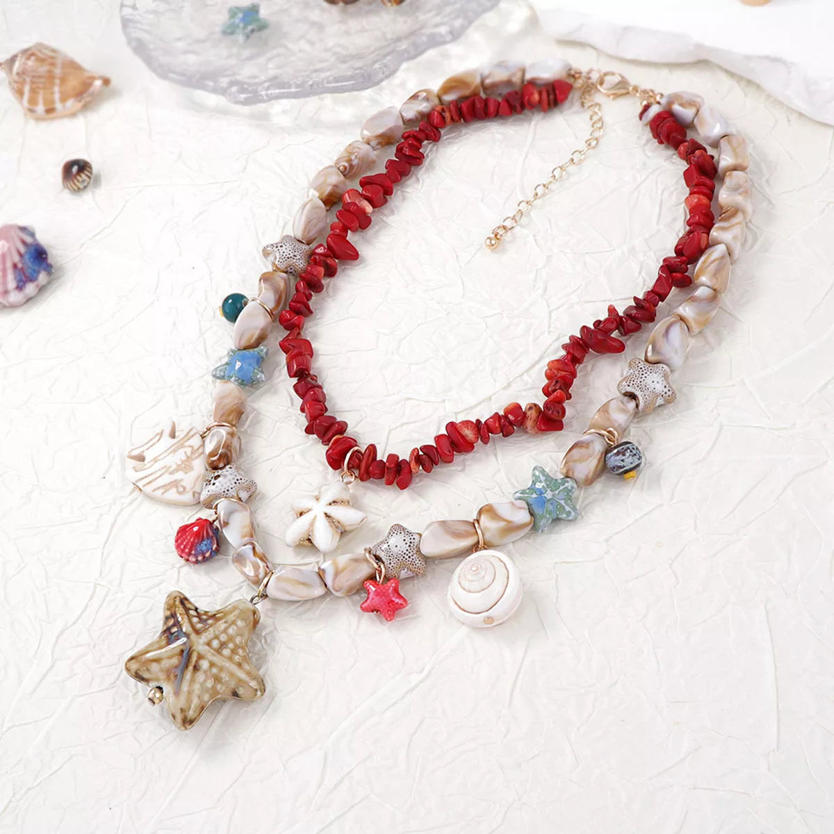 Red beaded multi-strand shell charm necklace with starfish, shell, and star pendants
