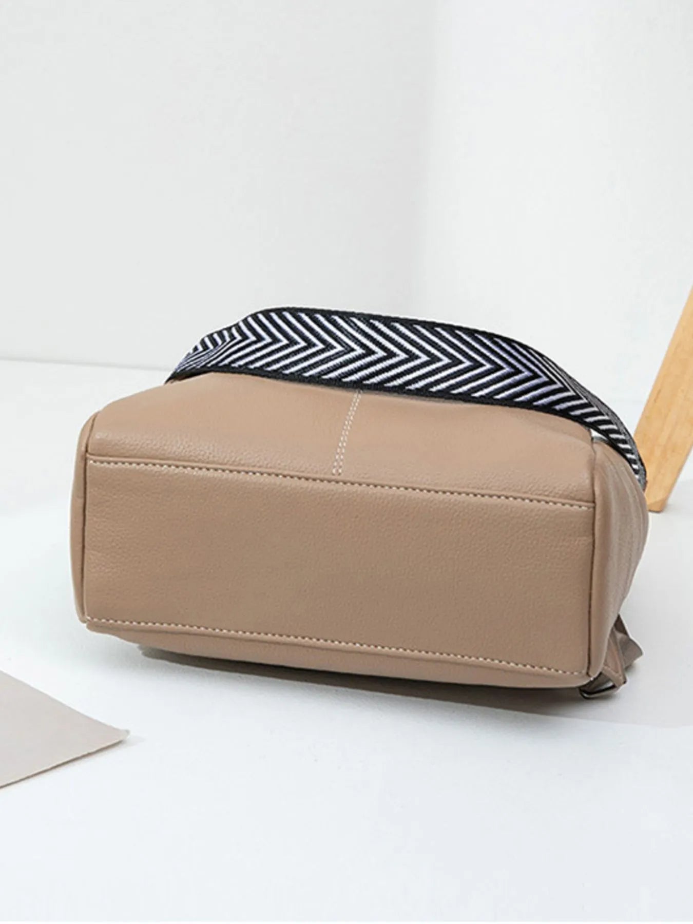 Beige leather backpack bag with rear horizontal zipper and chevron-trim shoulder strap