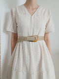 Woven braid belt with gold-tone irregular buckle, cinching the waist of a dress