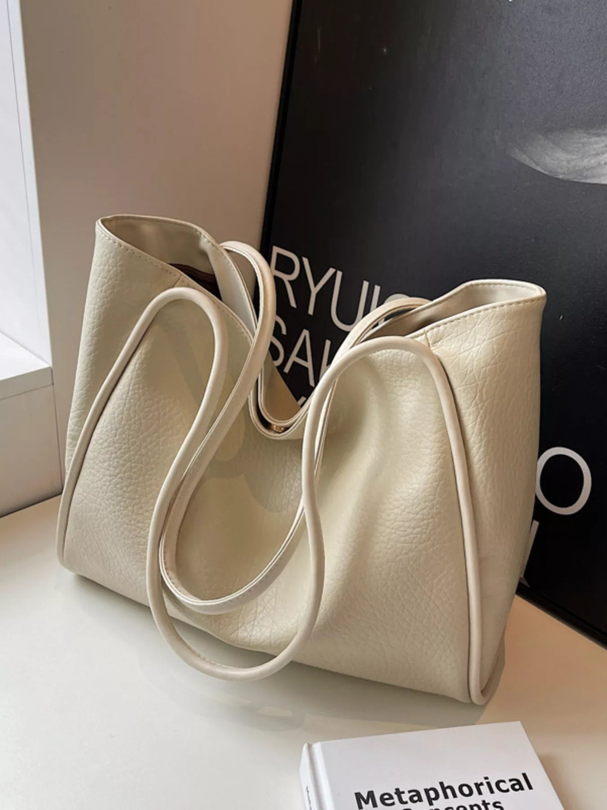 Off-white vegan leather tote bag with wide U-shaped straps and roomy open center