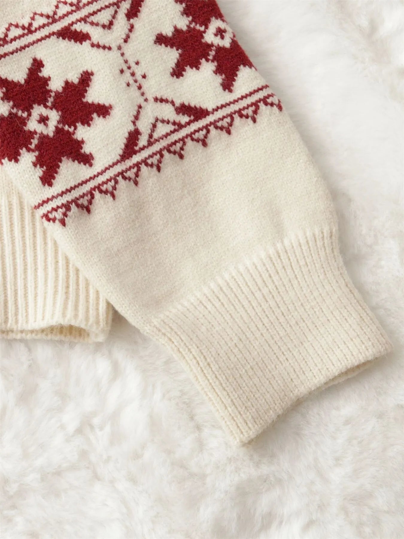 Round-neck sweater sleeve with ribbed cuff and red snowflake motif on white knit