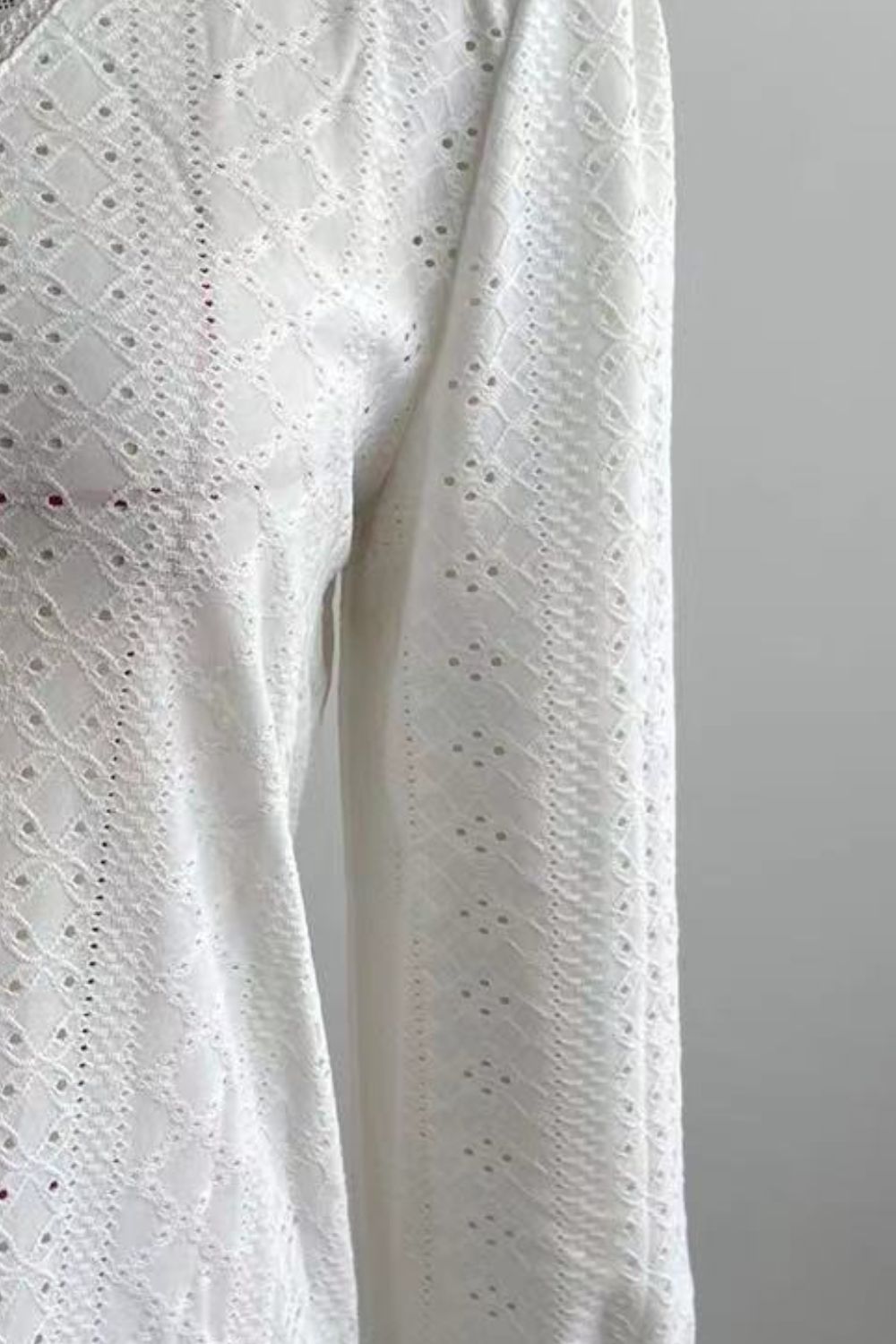 White eyelet blouse fabric detail with textured cutouts along sleeves