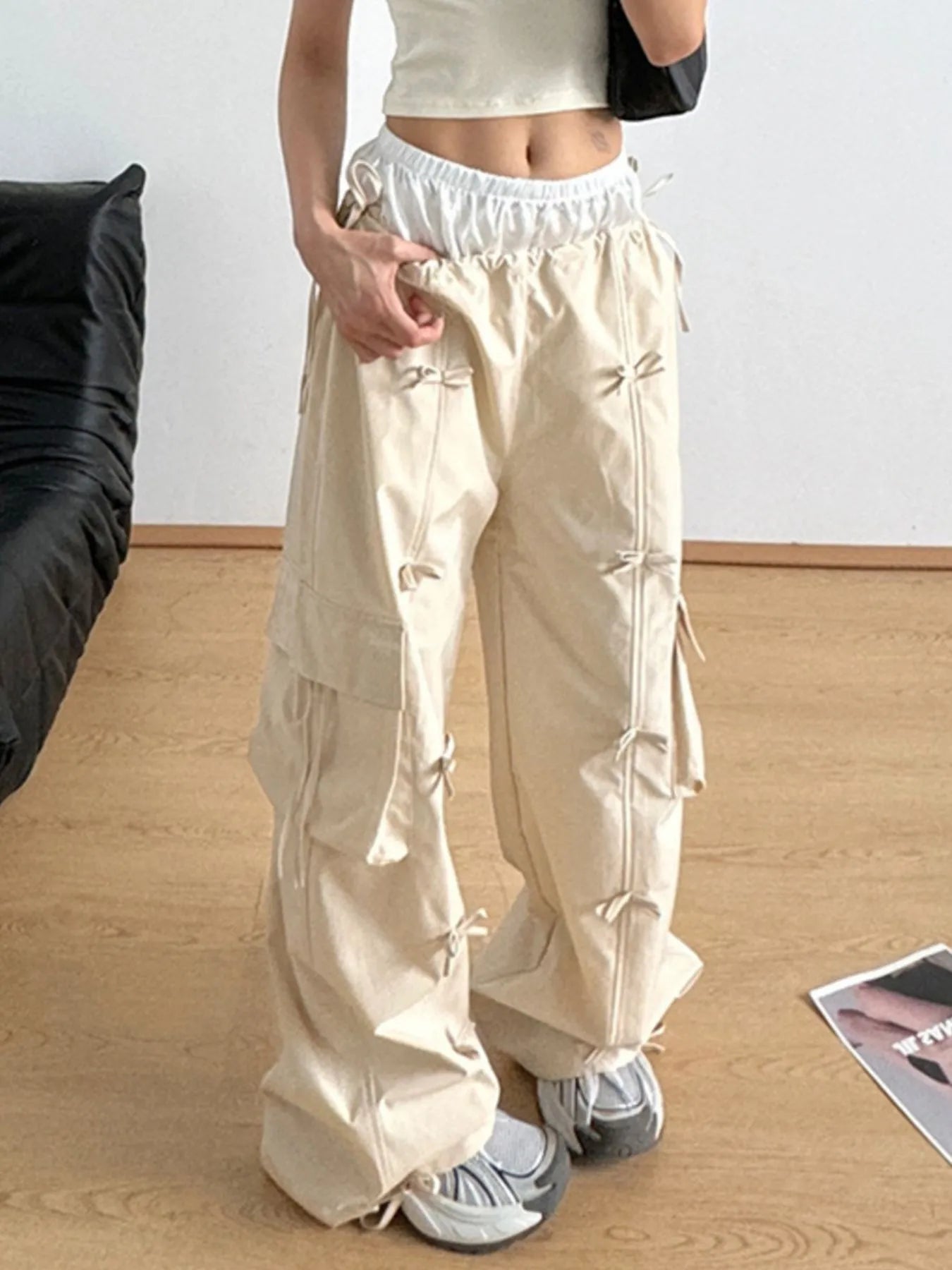 Tan elastic-waist cargo pants with front pockets and hanging tie straps at sides