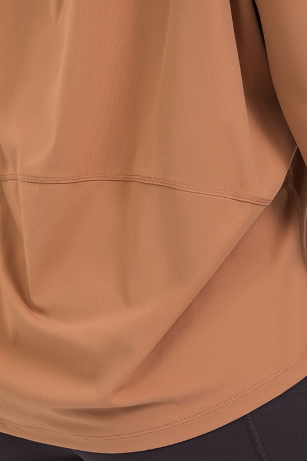 Loose-fit active top in dark tan, long sleeves with curved hem detail.