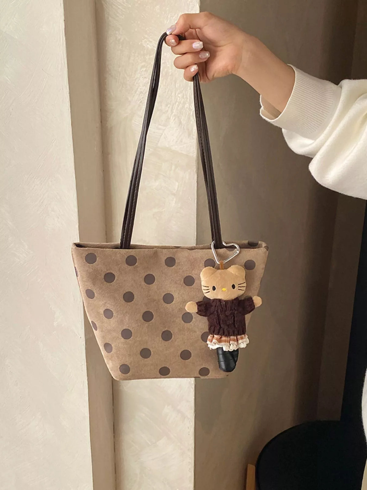 Tan suede shoulder handbag with dark polka dots and cat charm hanging