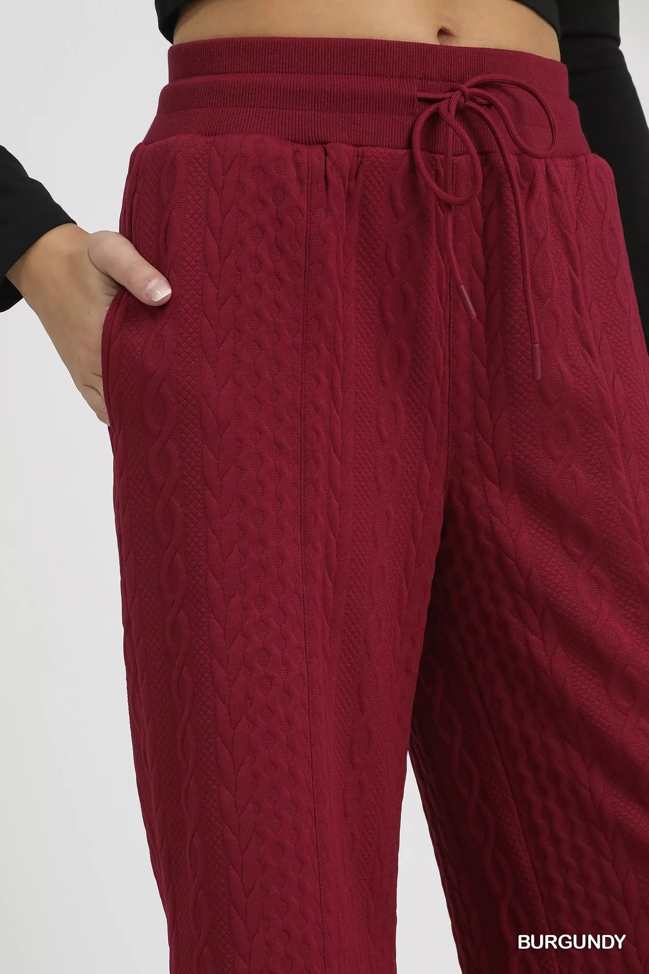 Burgundy cable knit pants close-up with gathered drawstring waist and texture