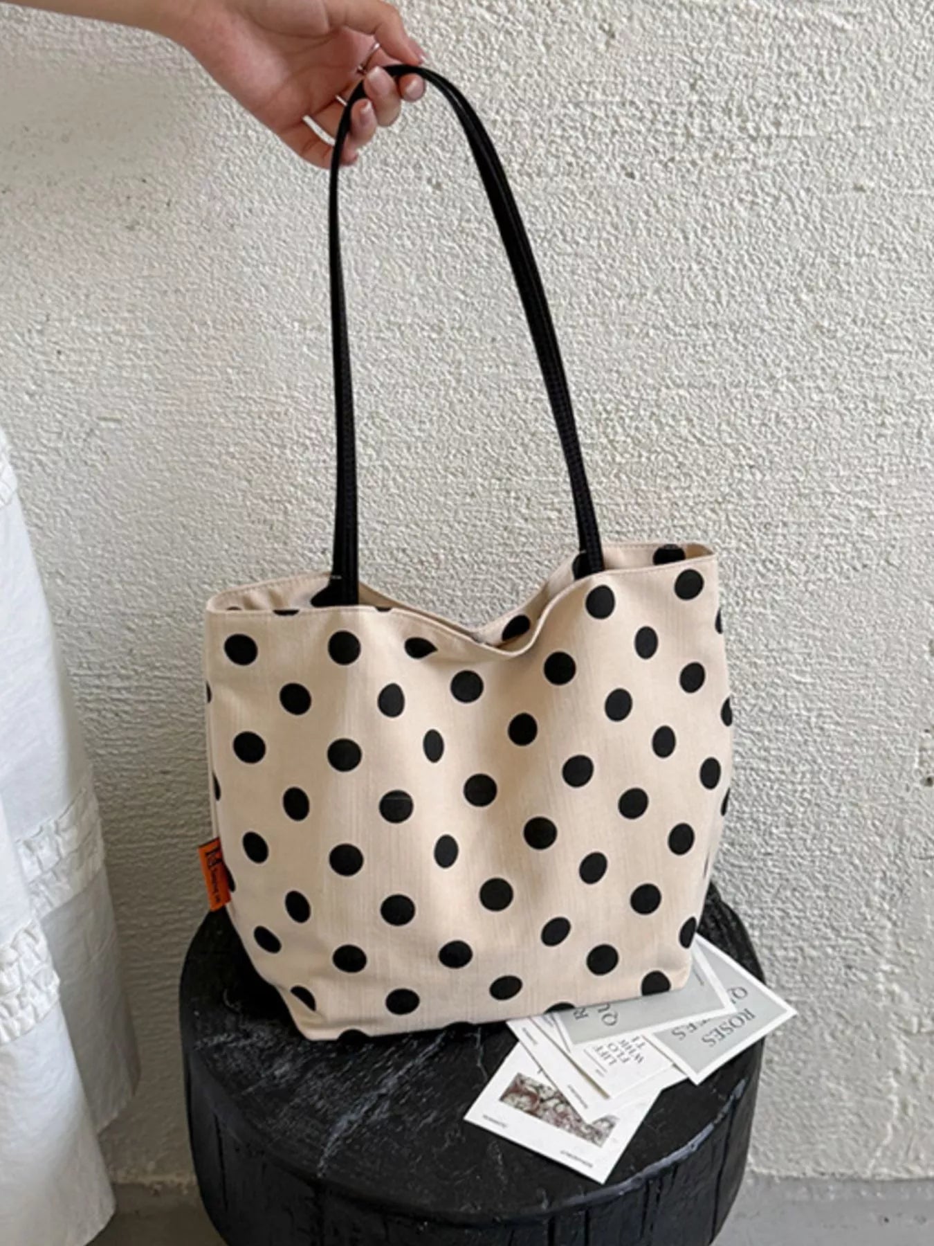 Cream medium polka dot tote bag with black dots, black handles, and inner lining