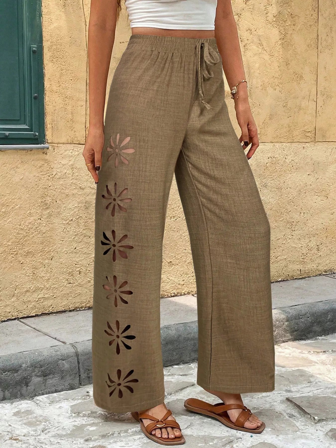 Brown wide-leg pants with drawstring waist and floral cutout motif along outer legs