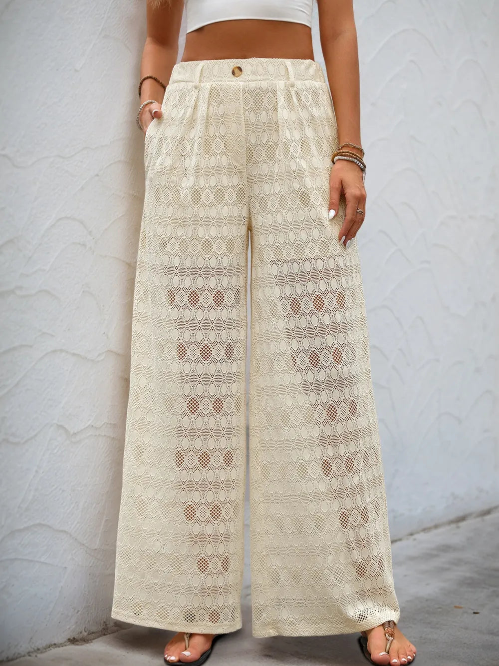 Cream wide-leg lace pants with decorative button waistband and allover embroidered geometric motif