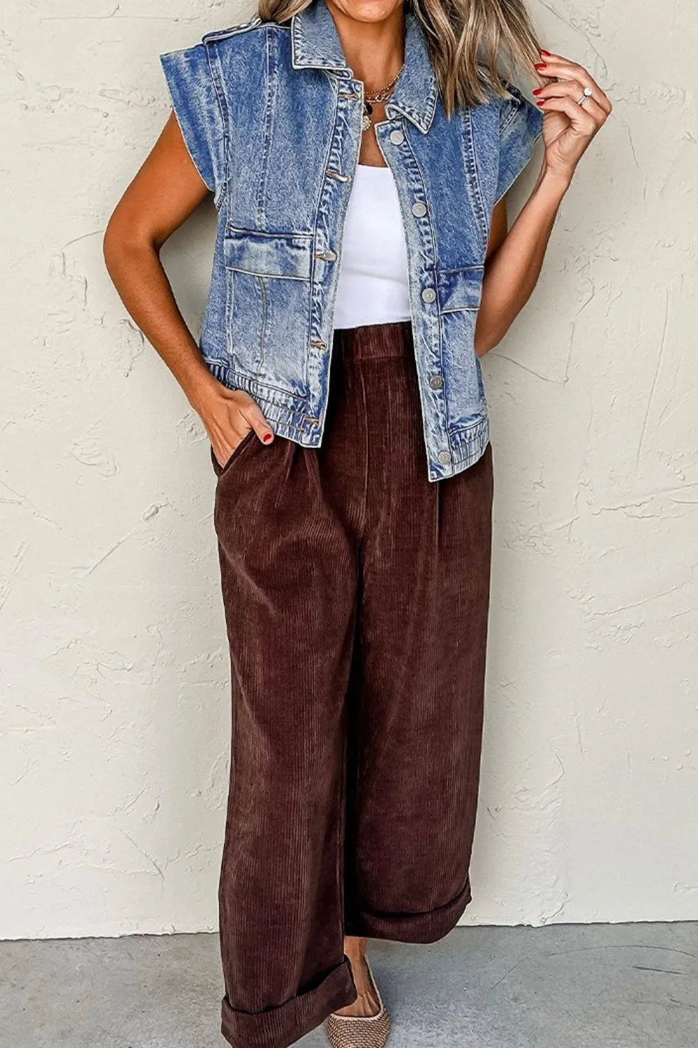 Medium-wash denim button-up cap sleeve jacket with pointed collar and front chest pockets