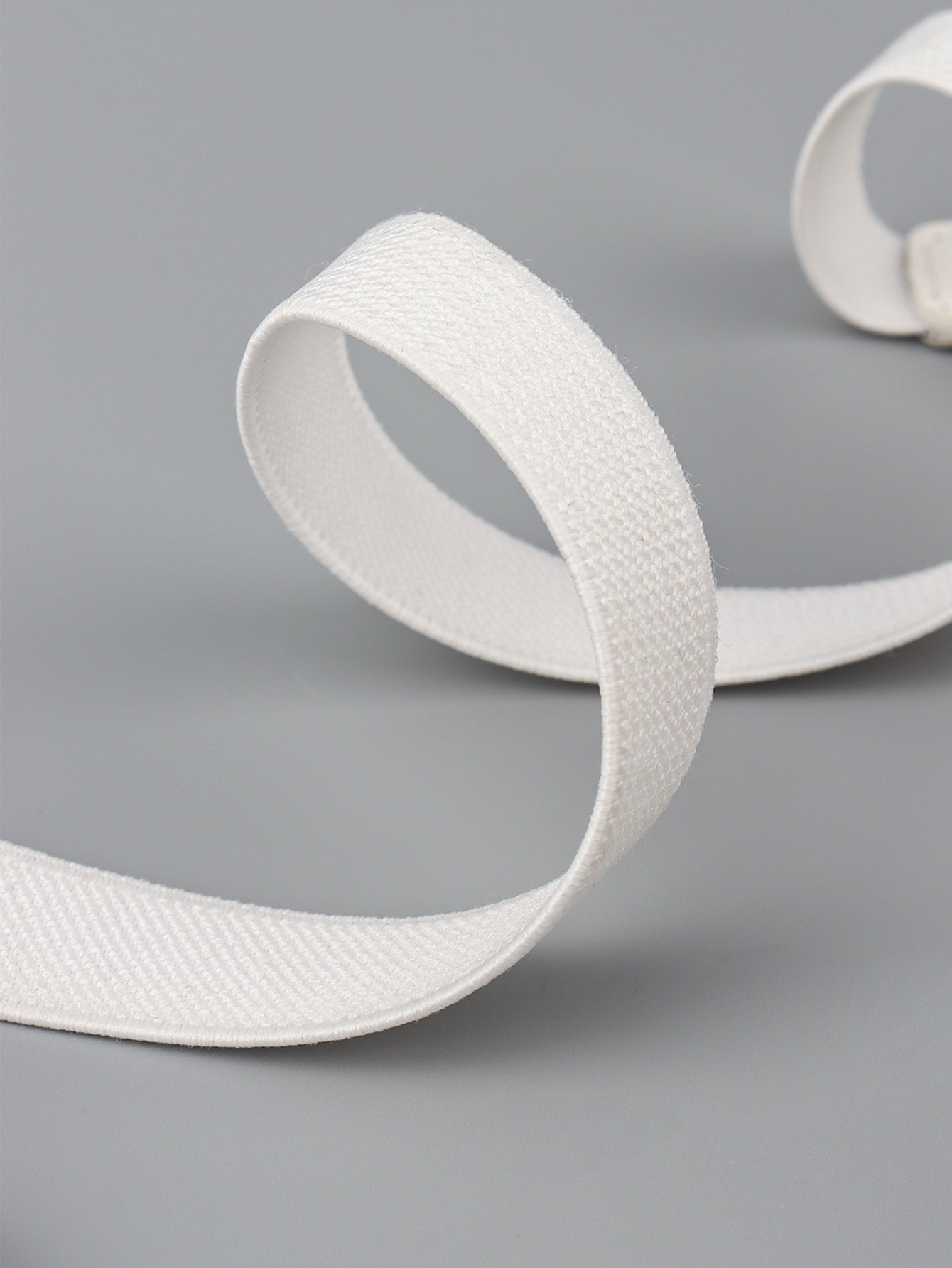 Elastic vegan leather skinny belt, white strap close-up with woven texture