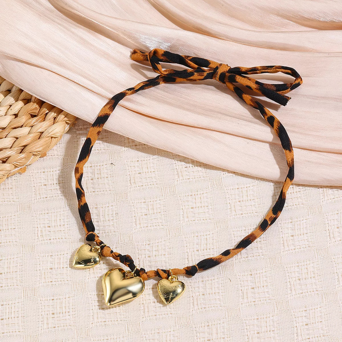Gold-plated heart necklace with leopard-print chain and three heart charms, close-up