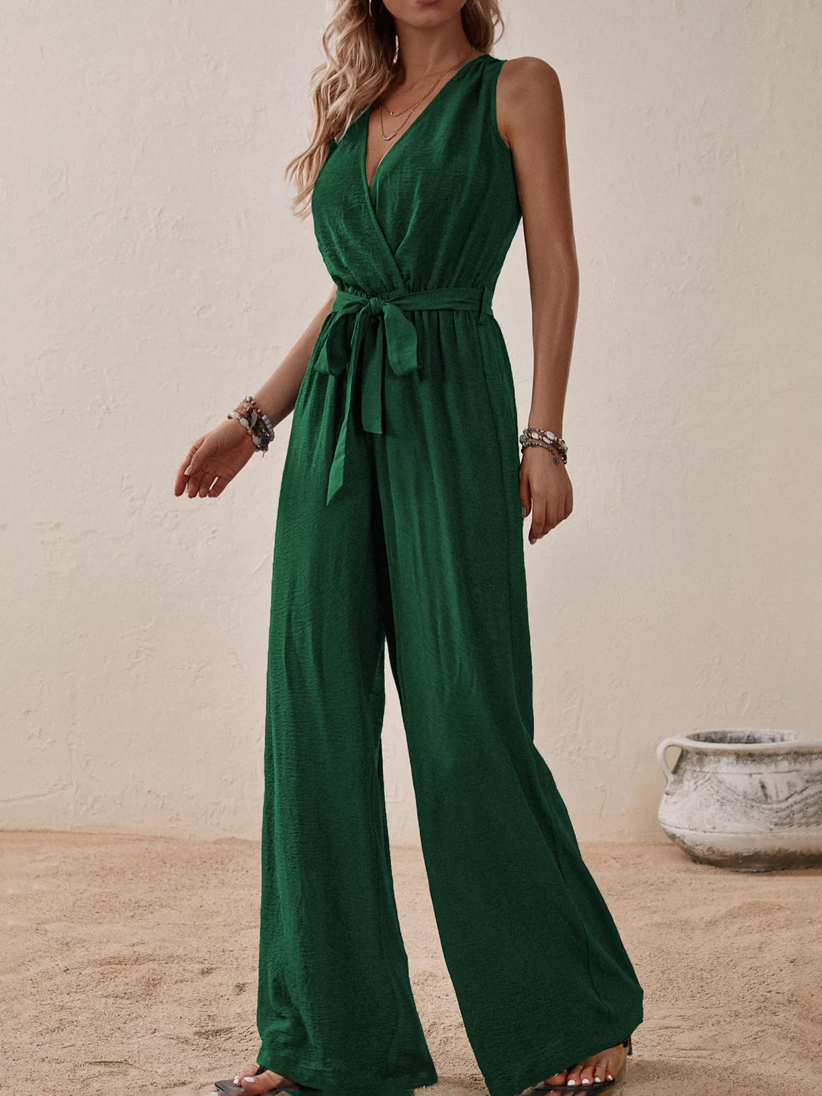 Dark green sleeveless V-neck tie-waist wide-leg jumpsuit with waist bow.