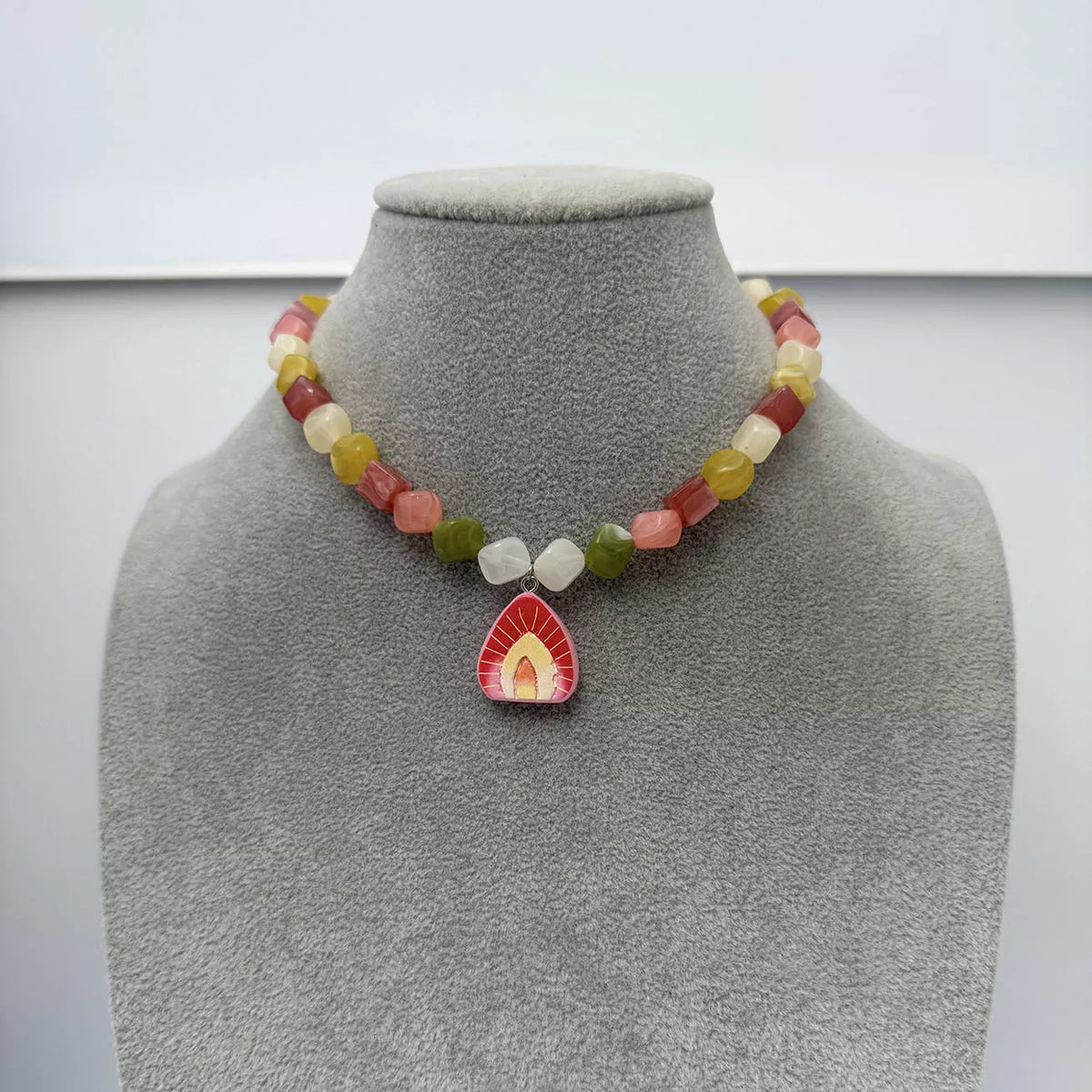 Necklace on a mannequin: multicolor beads with red resin arched pendant