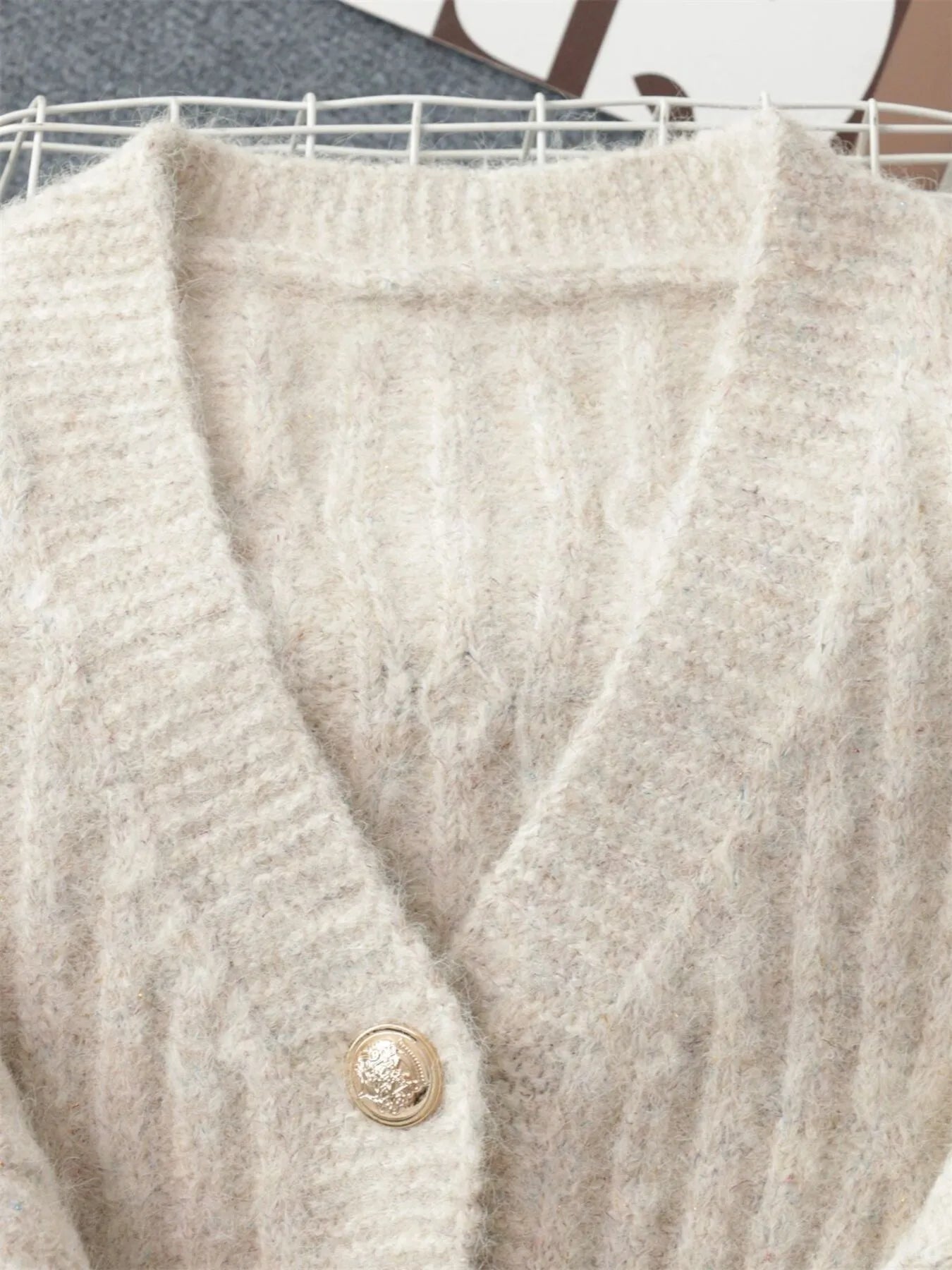 Cream cable knit V-neck cardigan close-up with gold-tone button detail