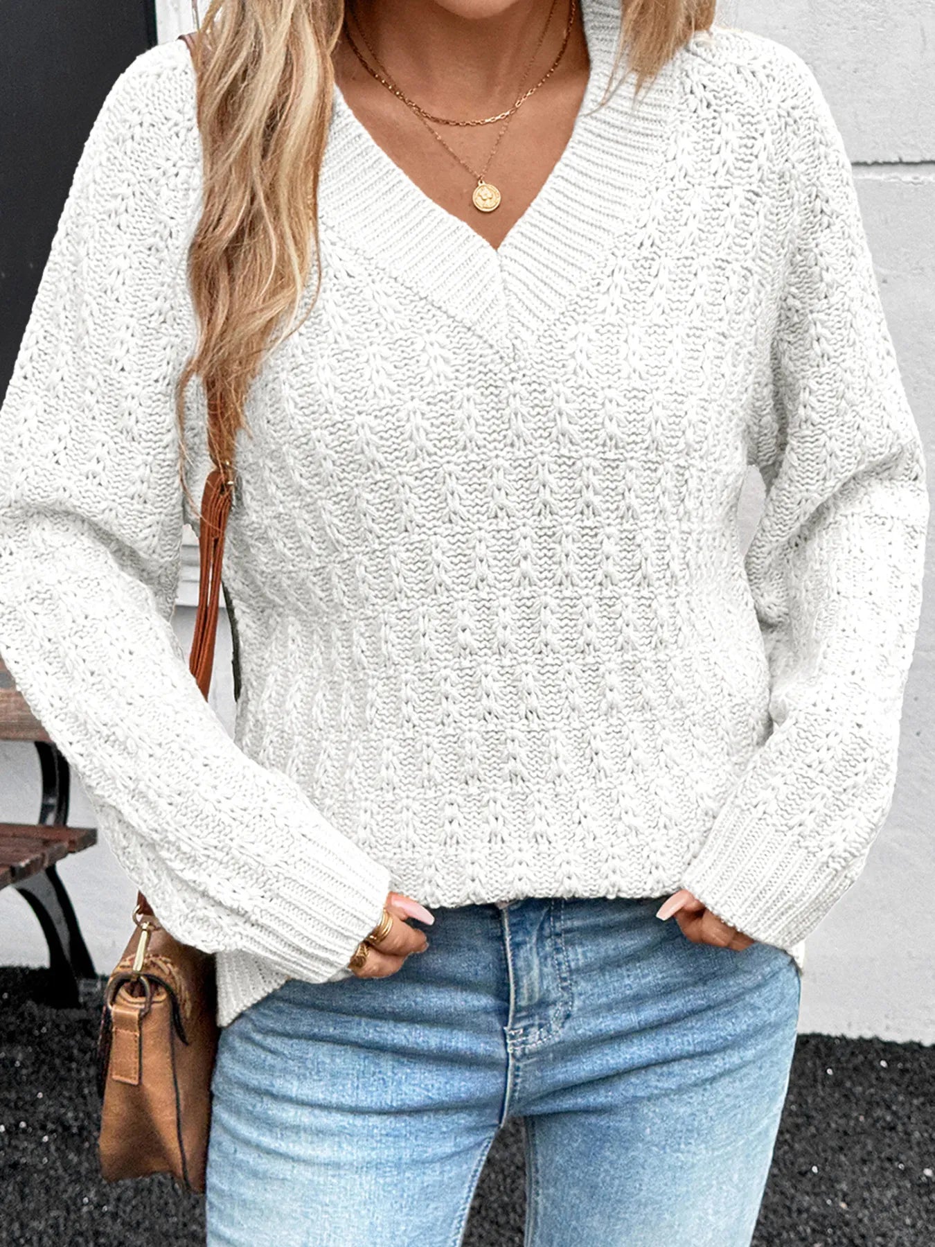 White textured knit V-neck sweater with long sleeves and ribbed hem detail.