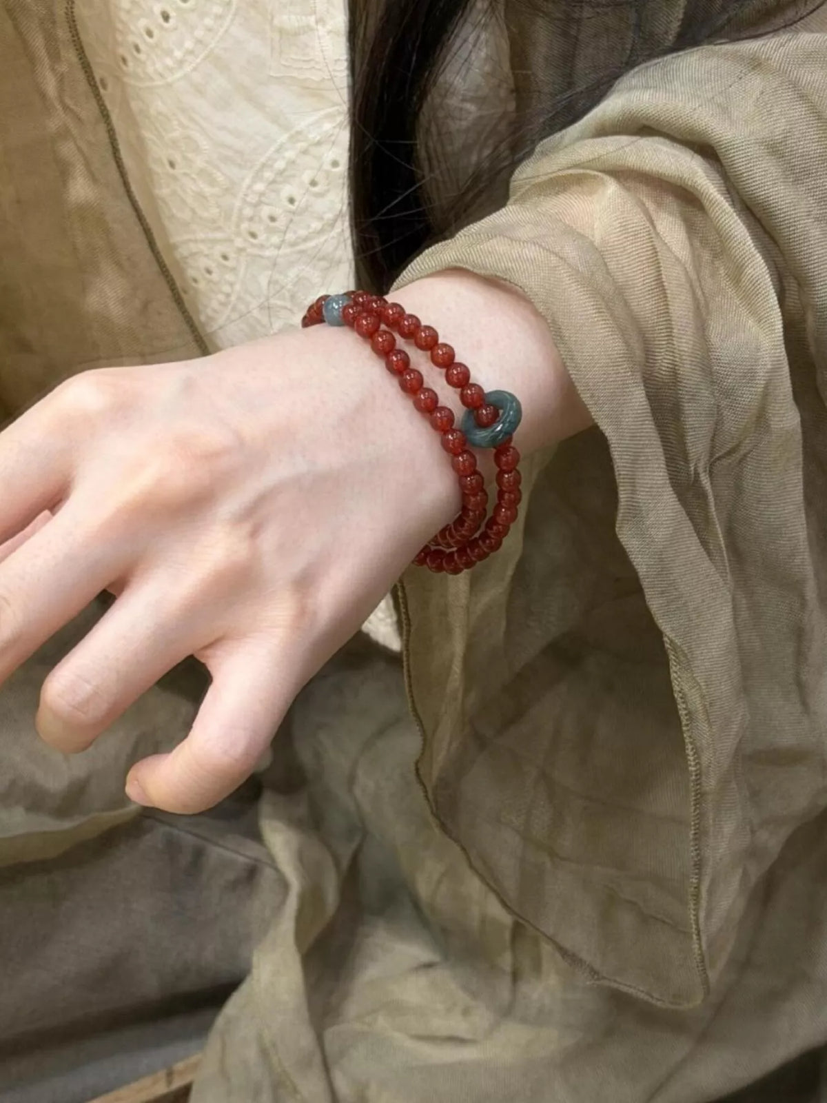 Double-layer agate bead bracelet in burgundy red with two teal accent beads on wrist