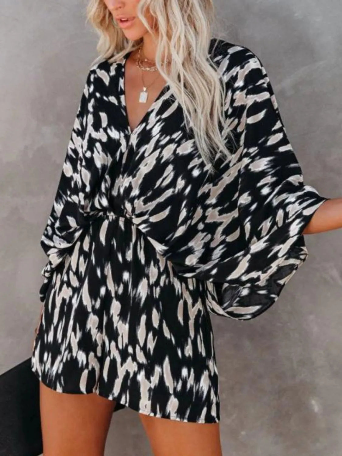 Leopard printed romper with V-neck, long loose sleeves, and gathered waist detail