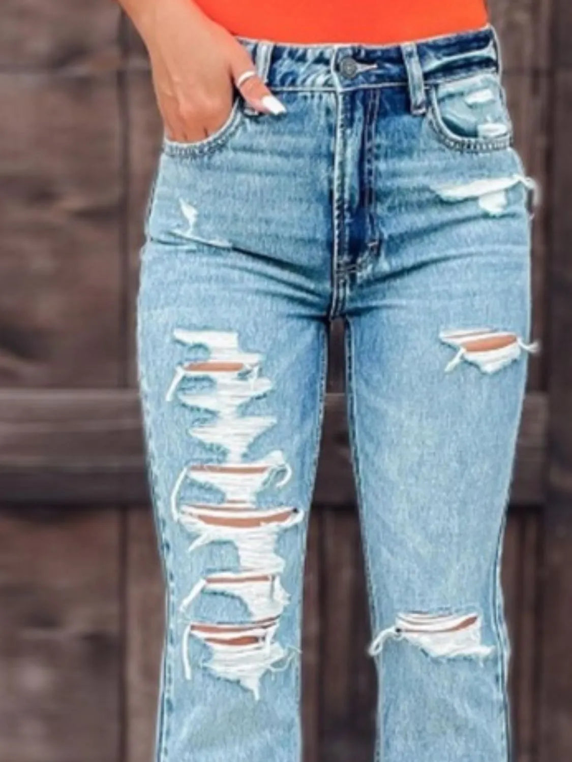 Light wash distressed bootcut jeans with large ripped knee panels and front pockets