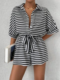 Black and white striped button-front romper with tie waist and cuffed short sleeves