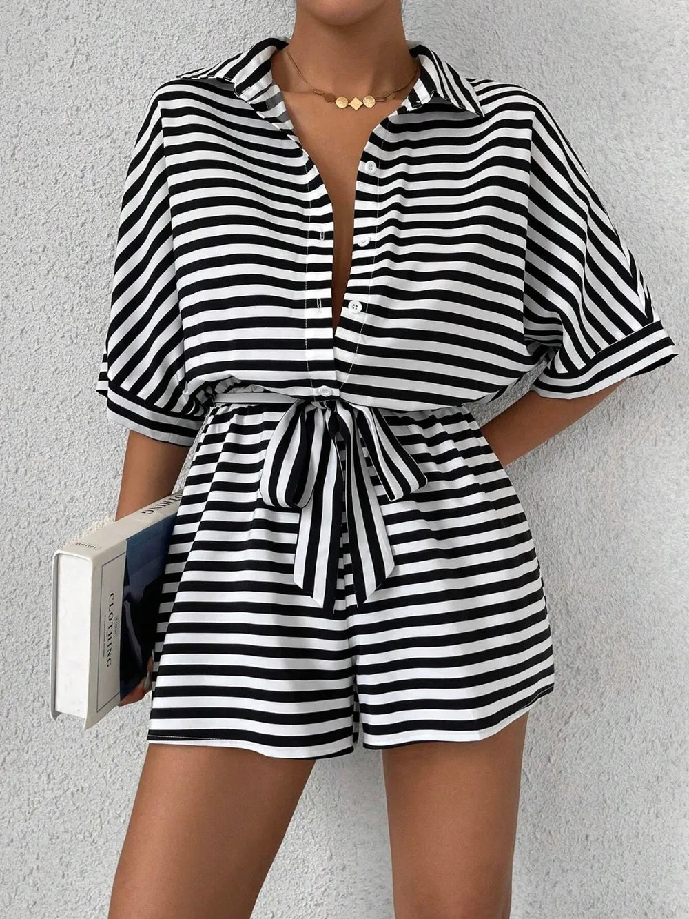 Black and white striped button-front romper with tie waist and cuffed short sleeves