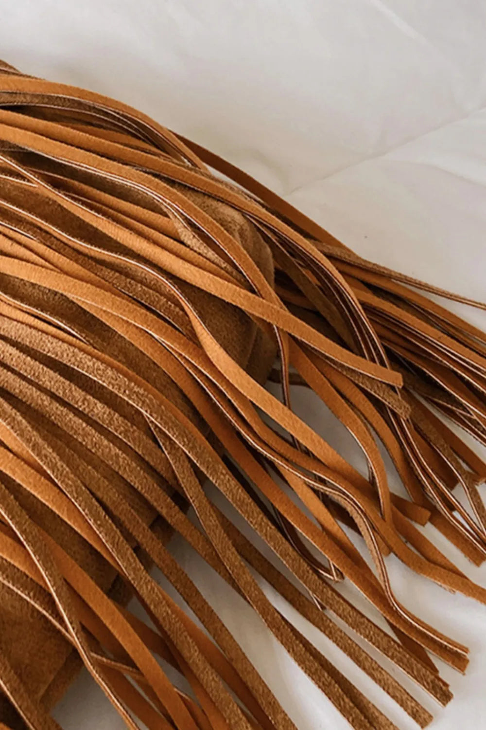 Close-up of tan suede fringe on a shoulder bag
