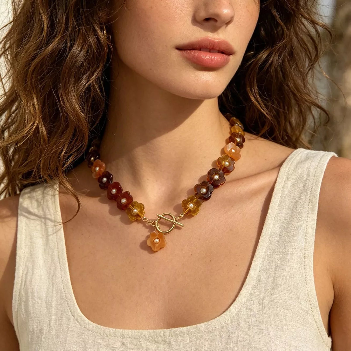 Gold beaded necklace with dark brown and amber resin flower beads and charm drop