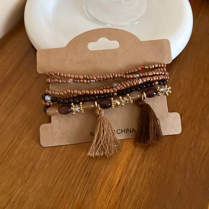 Beaded tassel rice bracelet set with brown, black, and gold-tone accents and charms