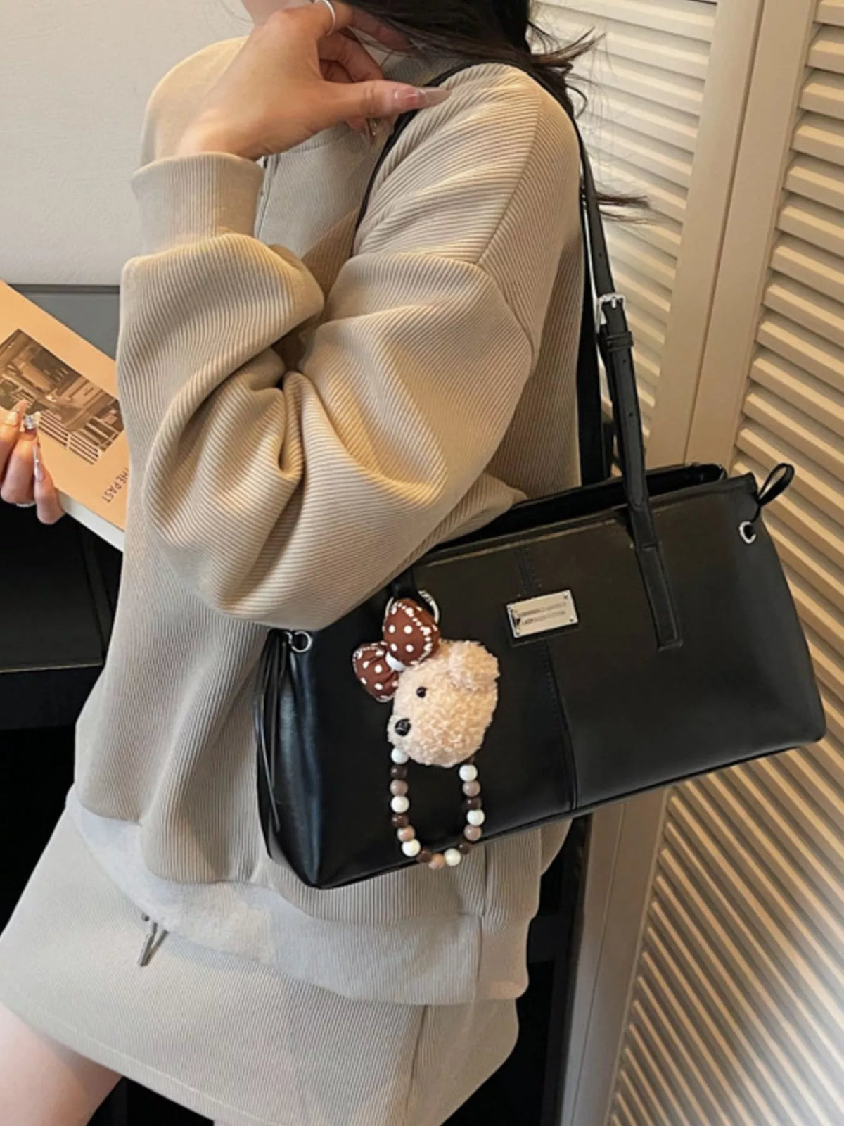 Black vegan leather medium shoulder bag worn on shoulder with front teddy charm
