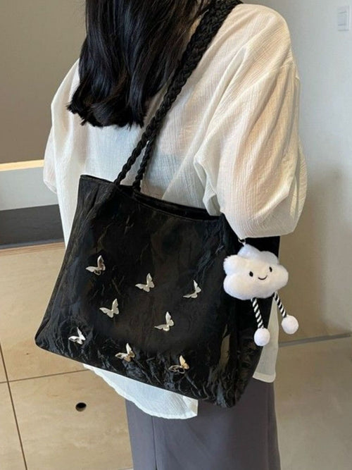 Black butterfly-pattern tote bag with braided strap and white plush hanging charm