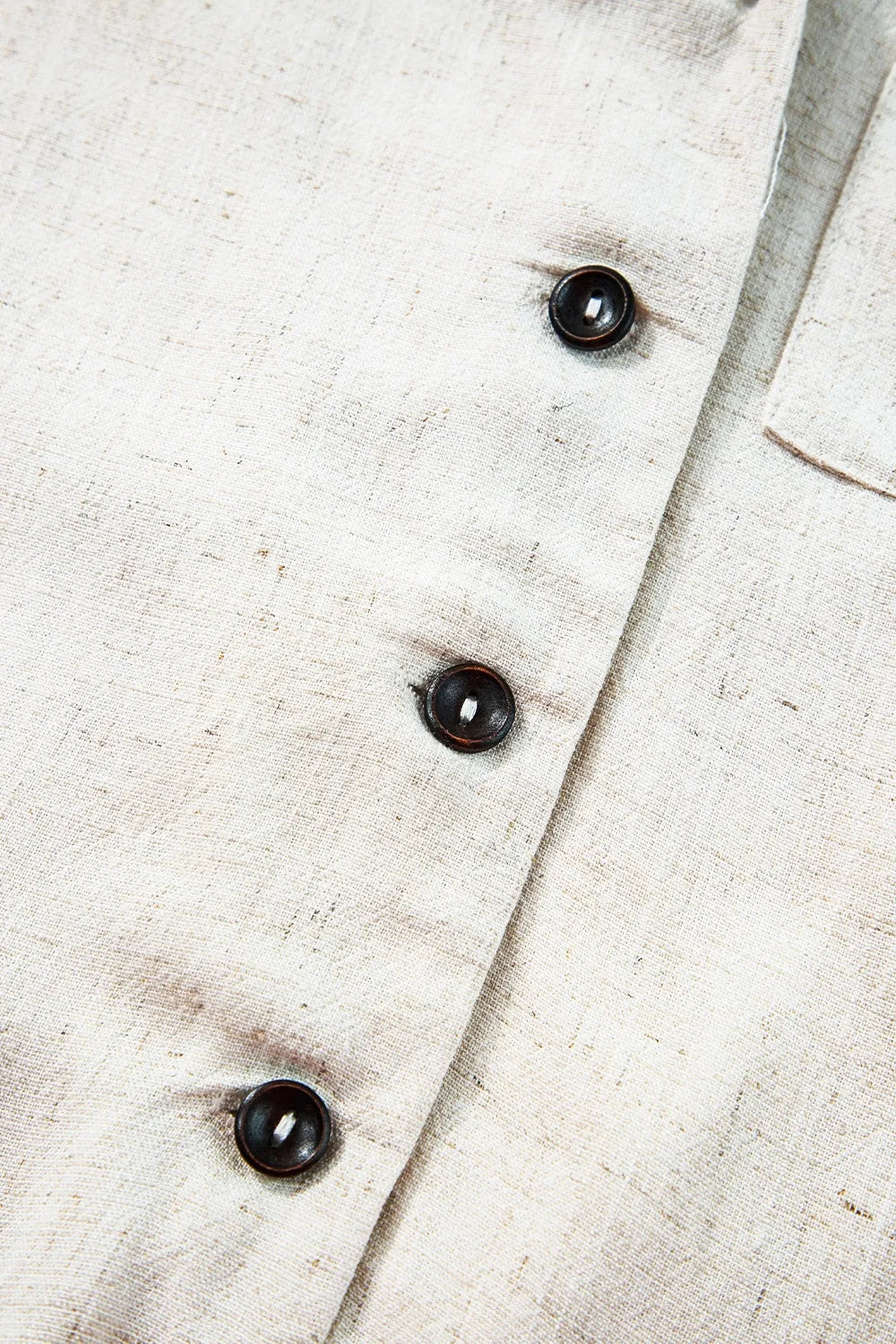Light beige romper with three dark round buttons on front placket