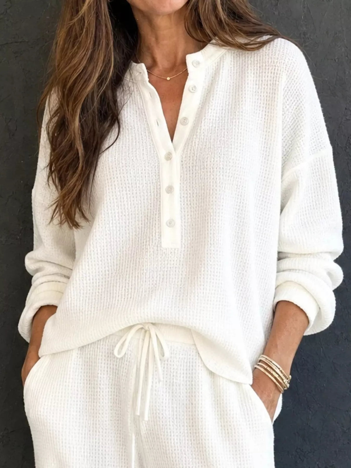 White waffle-knit henley top with front buttons and long sleeves, paired with drawstring pants.