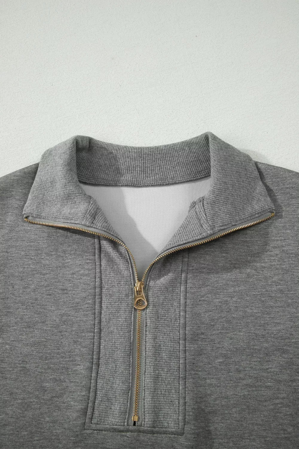 Dark gray half-zip polo top with ribbed collar and gold-tone zipper hardware.