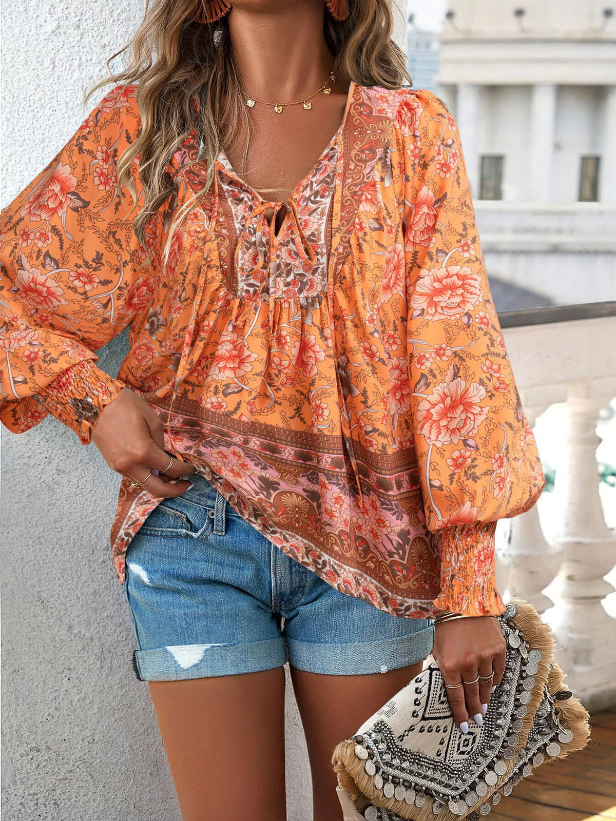 Orange floral tie-neck blouse with smocked cuffs, gathered front and border print