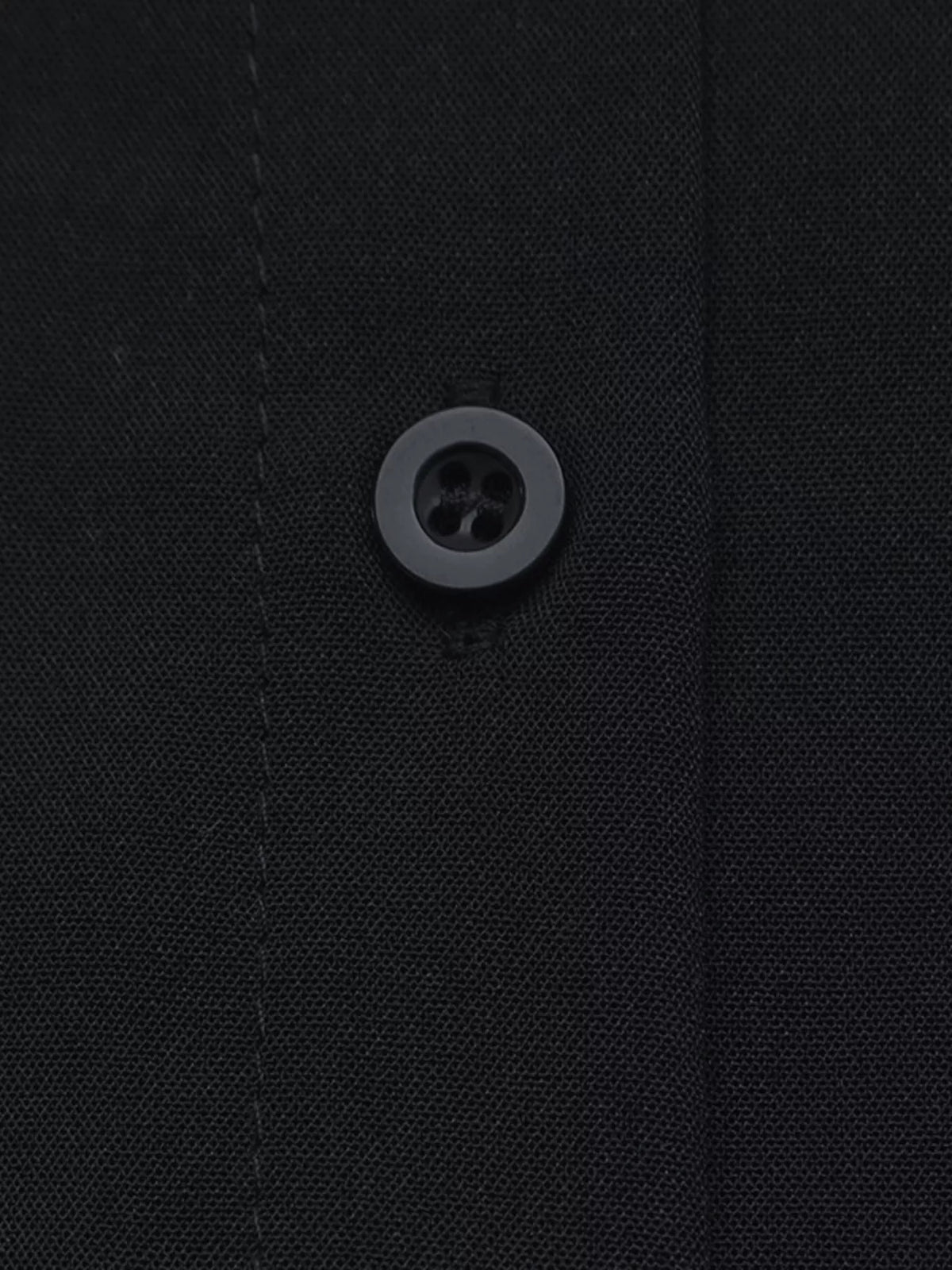 Close-up of black button detail on the shirt collar placket
