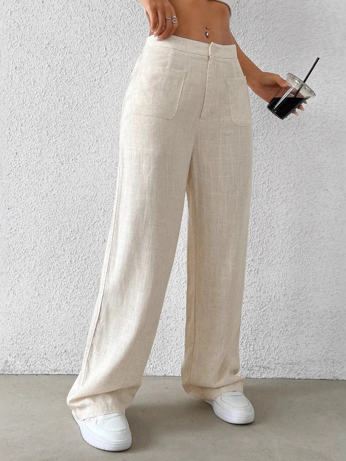 Beige wide-leg pants with two front pockets and draped straight wide legs.