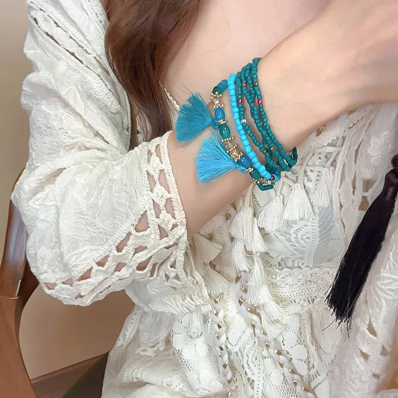 Blue bead tassel bracelet on wrist with layered strands and small tassel details