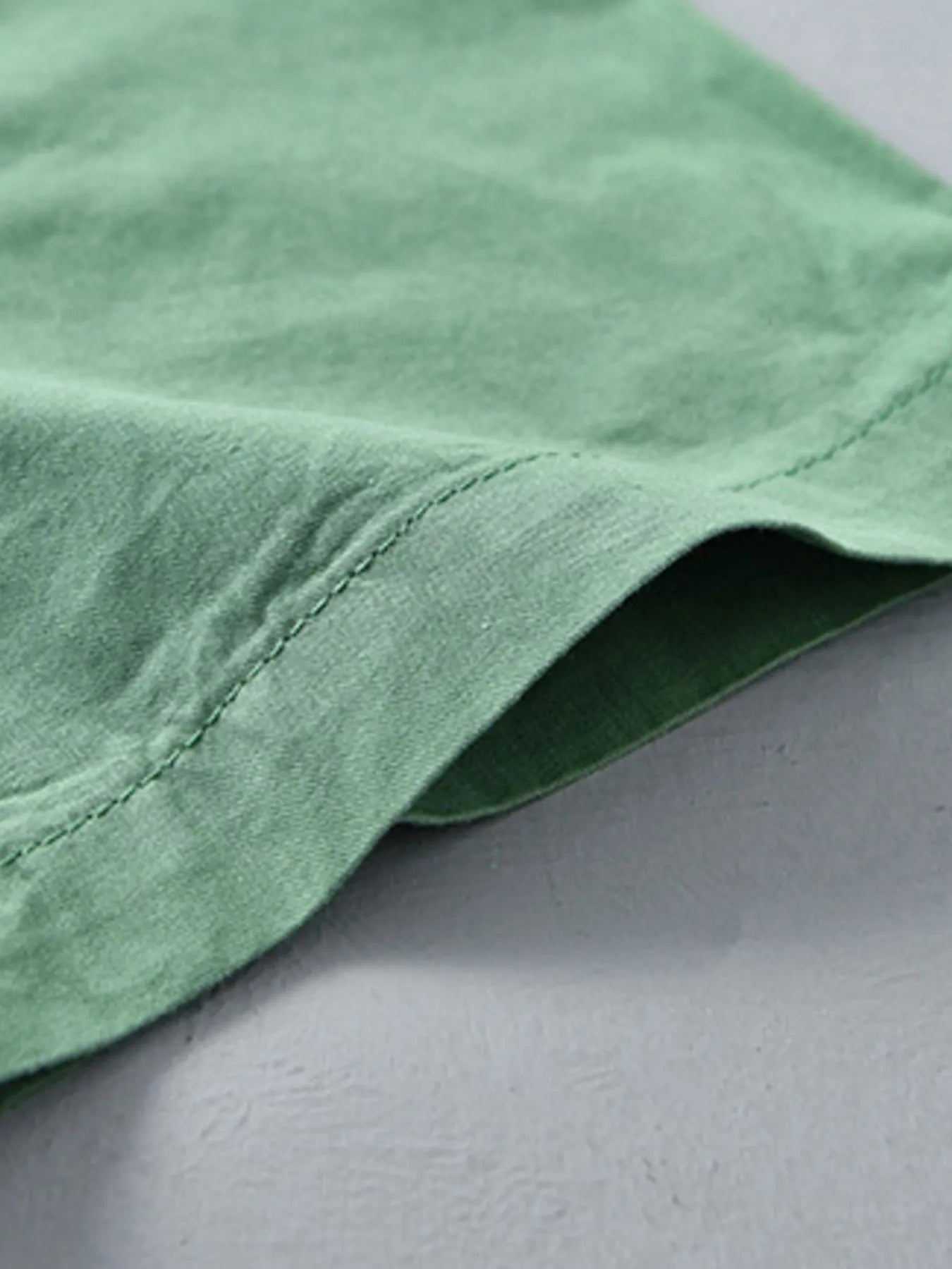 Green short-sleeve button-up shirt side seam and stitched hem