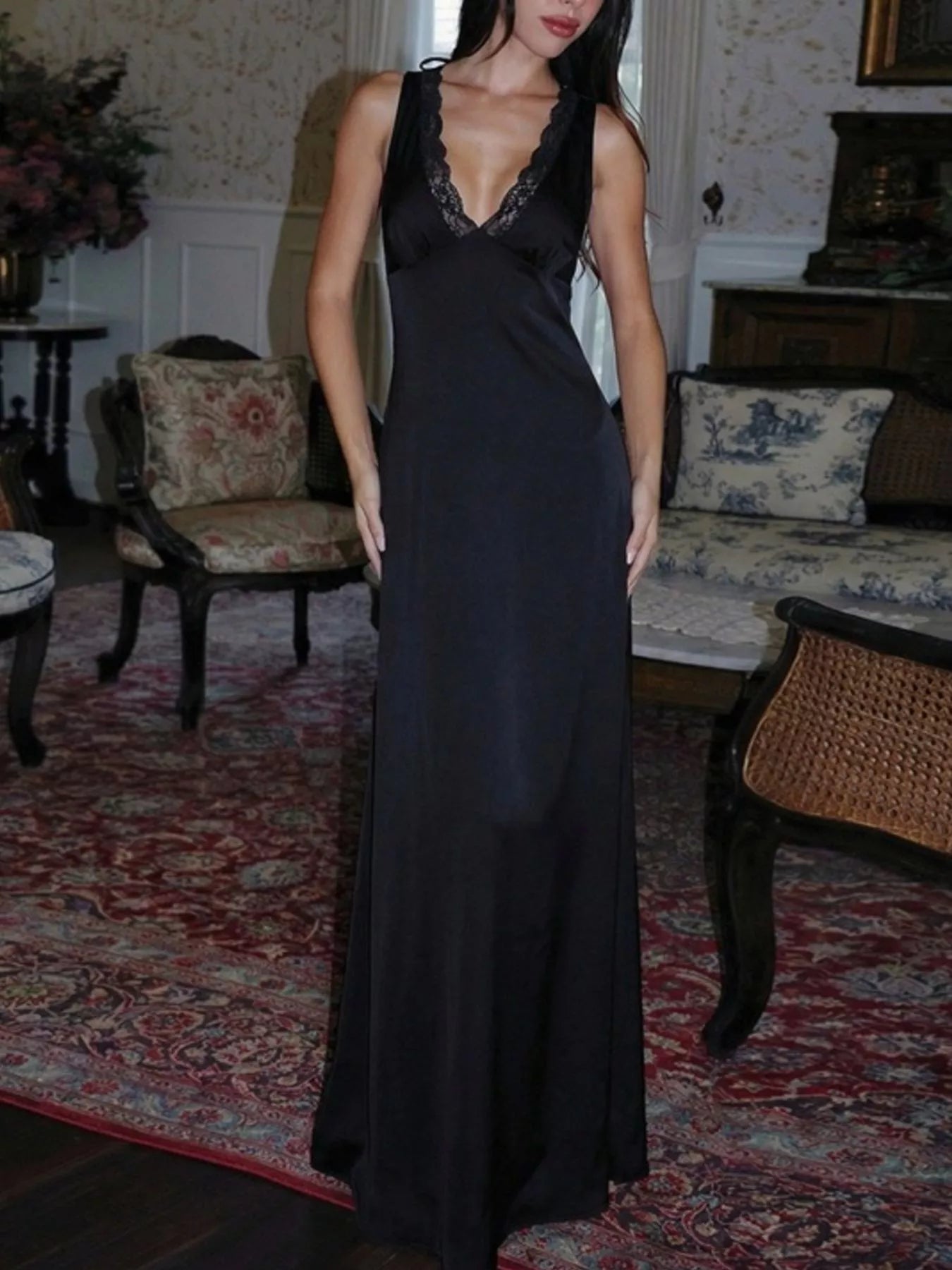 Black sleeveless maxi dress with lace-trim V neckline and a fitted, floor-length hem.
