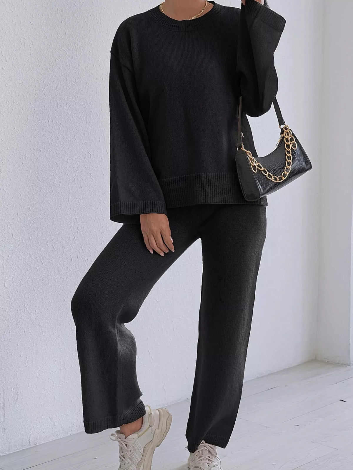 Black knit sweater and pants set with dropped shoulders, crew neck, and ribbed cuffs.