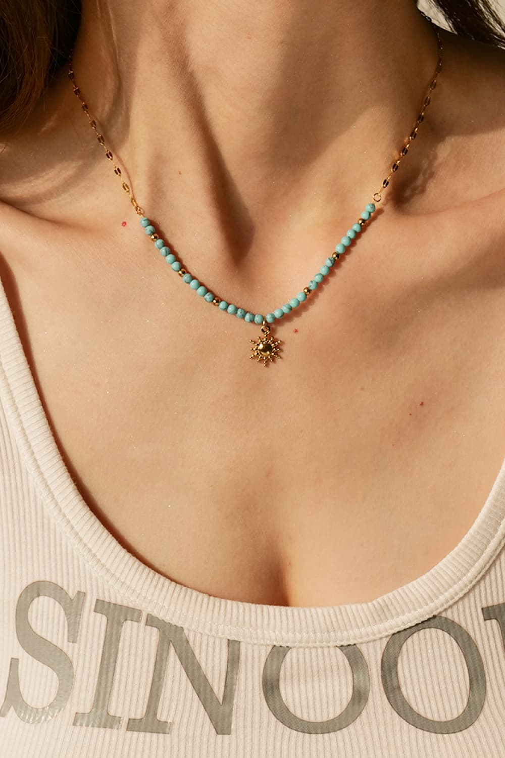 Turquoise beaded gold necklace with sun pendant charm on neckline